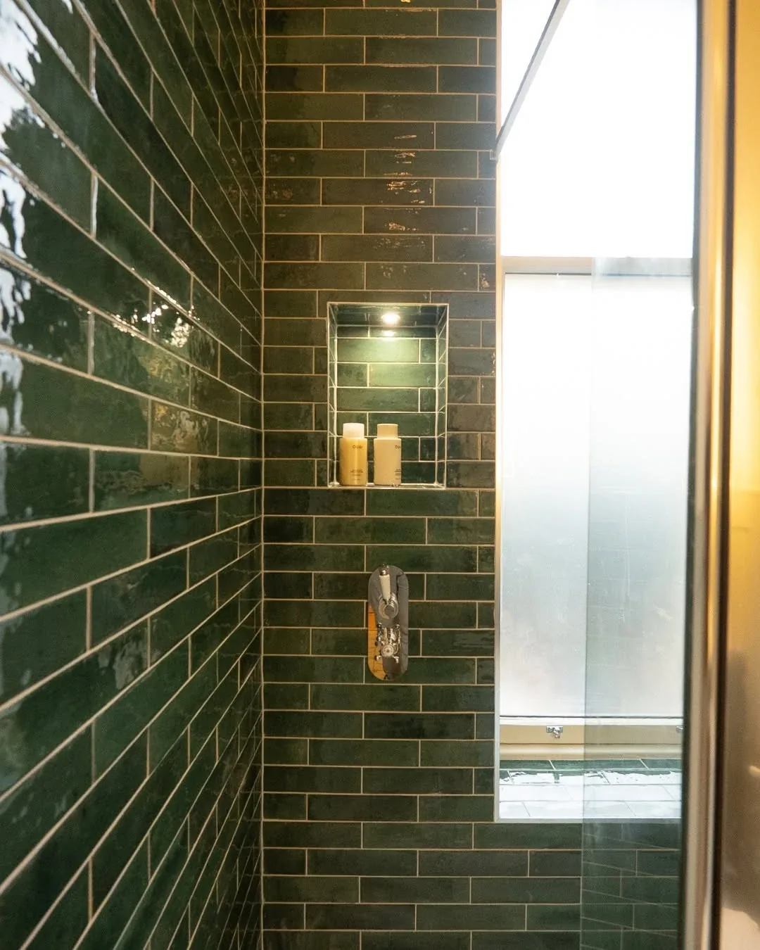 Lit shower niche and thermostatic shower valve set into green metro tiles in a Cardiff shower room