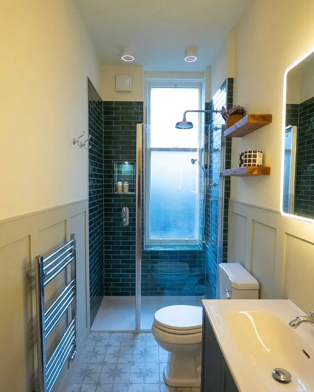 Walk-in shower with a rainfall head and green metro tiles on a bathroom fitted in Cardiff